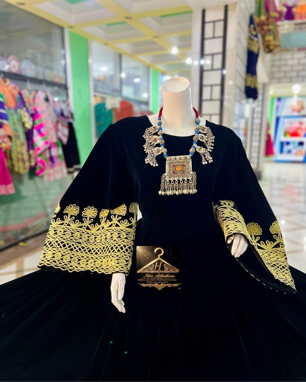 Black Afghan dress with gold embroidery on a mannequin inside the Idrisclotheshouse store
